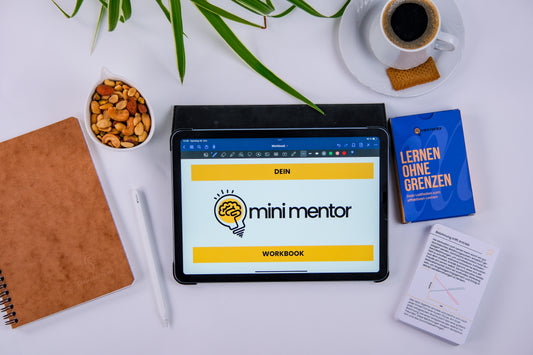 Ein Schreibtisch mit einem Kartendeck mit den besten Lerntipps, Kaffee, einem Notizbuch, eine schale Nüsse und einer Pflanze und einem iPad